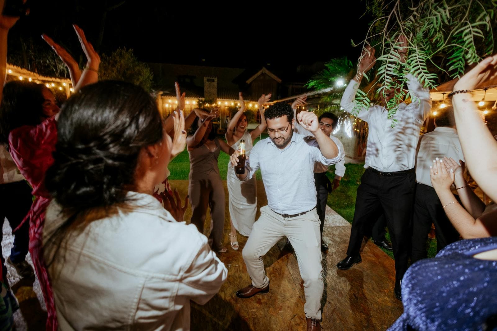 Wedding guests dancing and celebrating together under string lights at night
