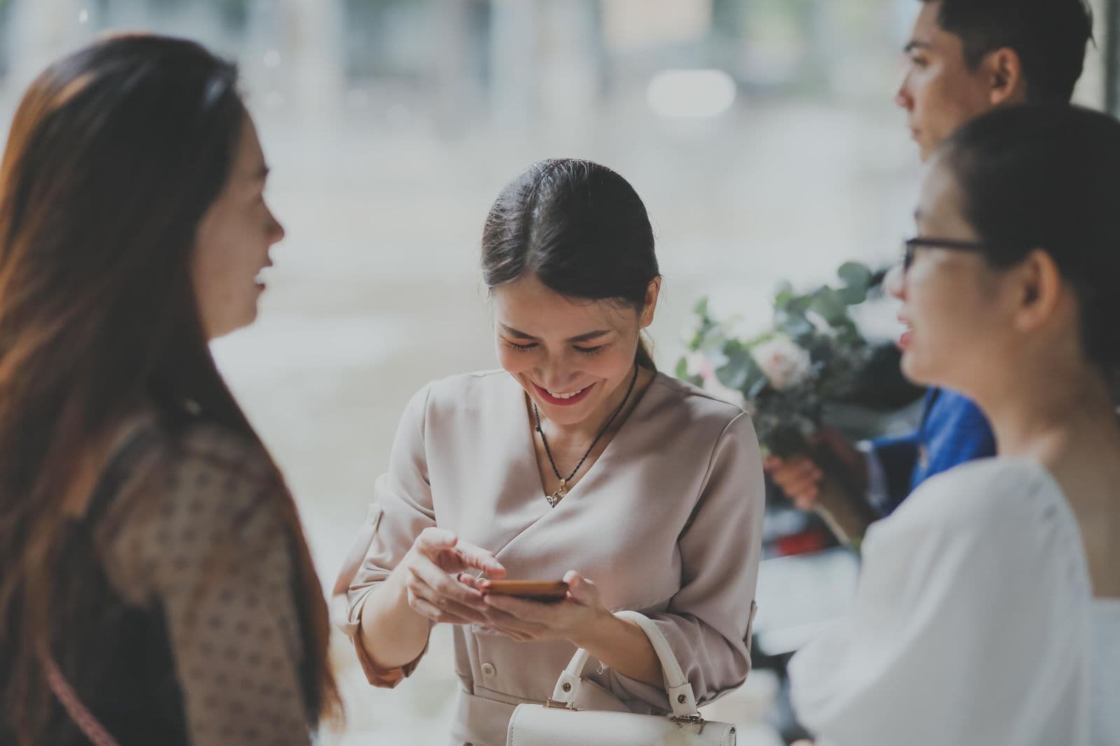 A wedding guest smiling as she looks at photos on her phone