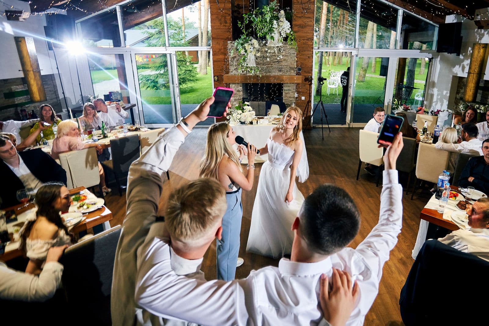 Wedding guests holding up their phones to capture the bride at the reception