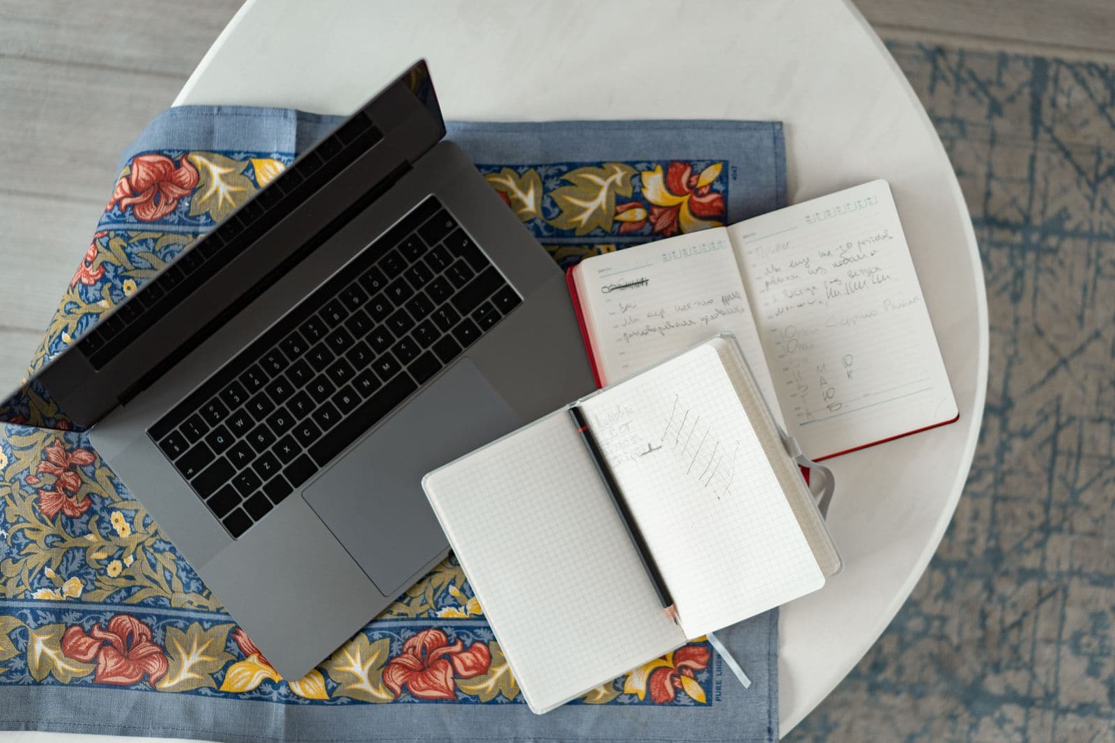 A laptop and notebooks on a table while researching wedding photo apps