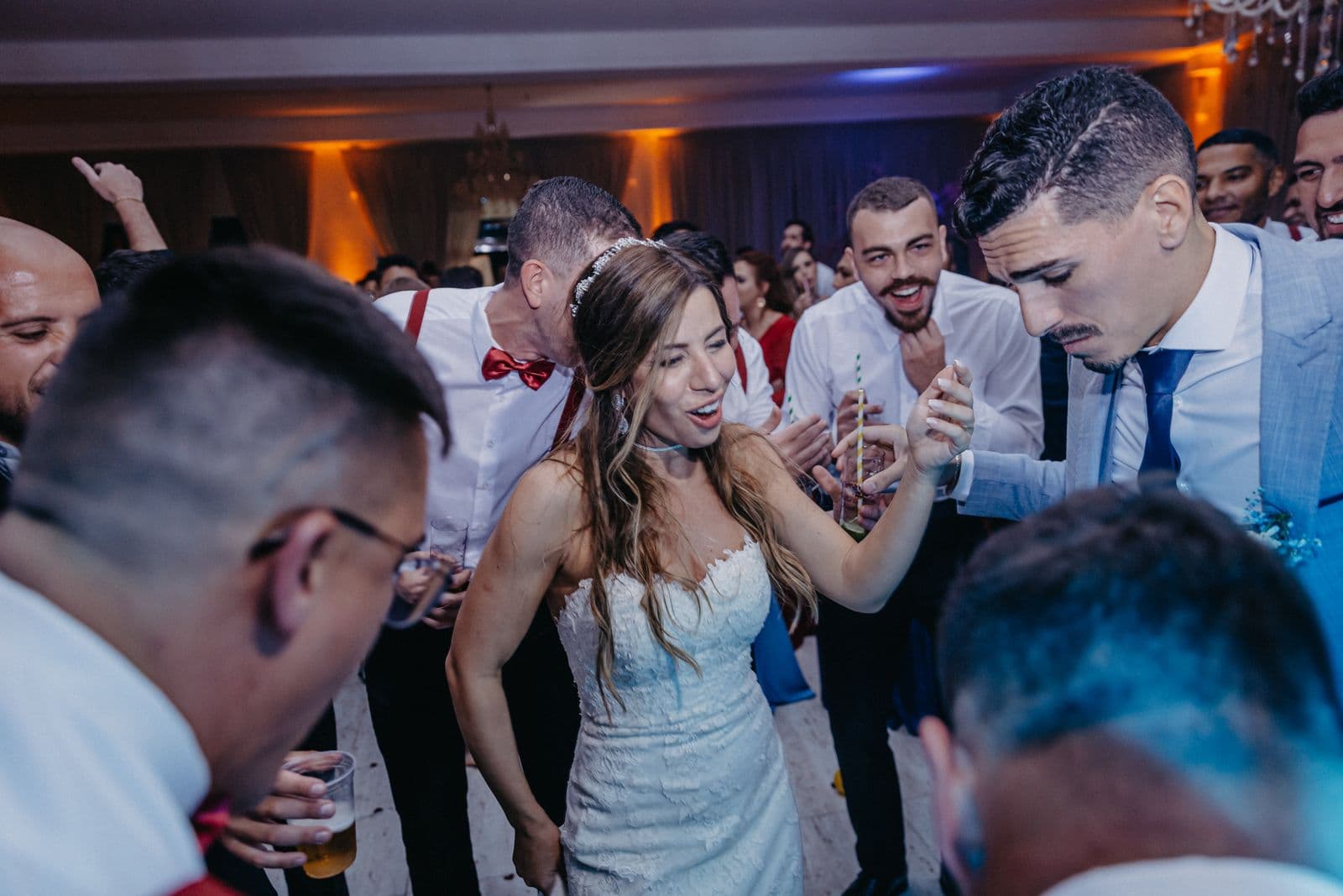 A bride dancing with guests on a packed wedding reception dance floor