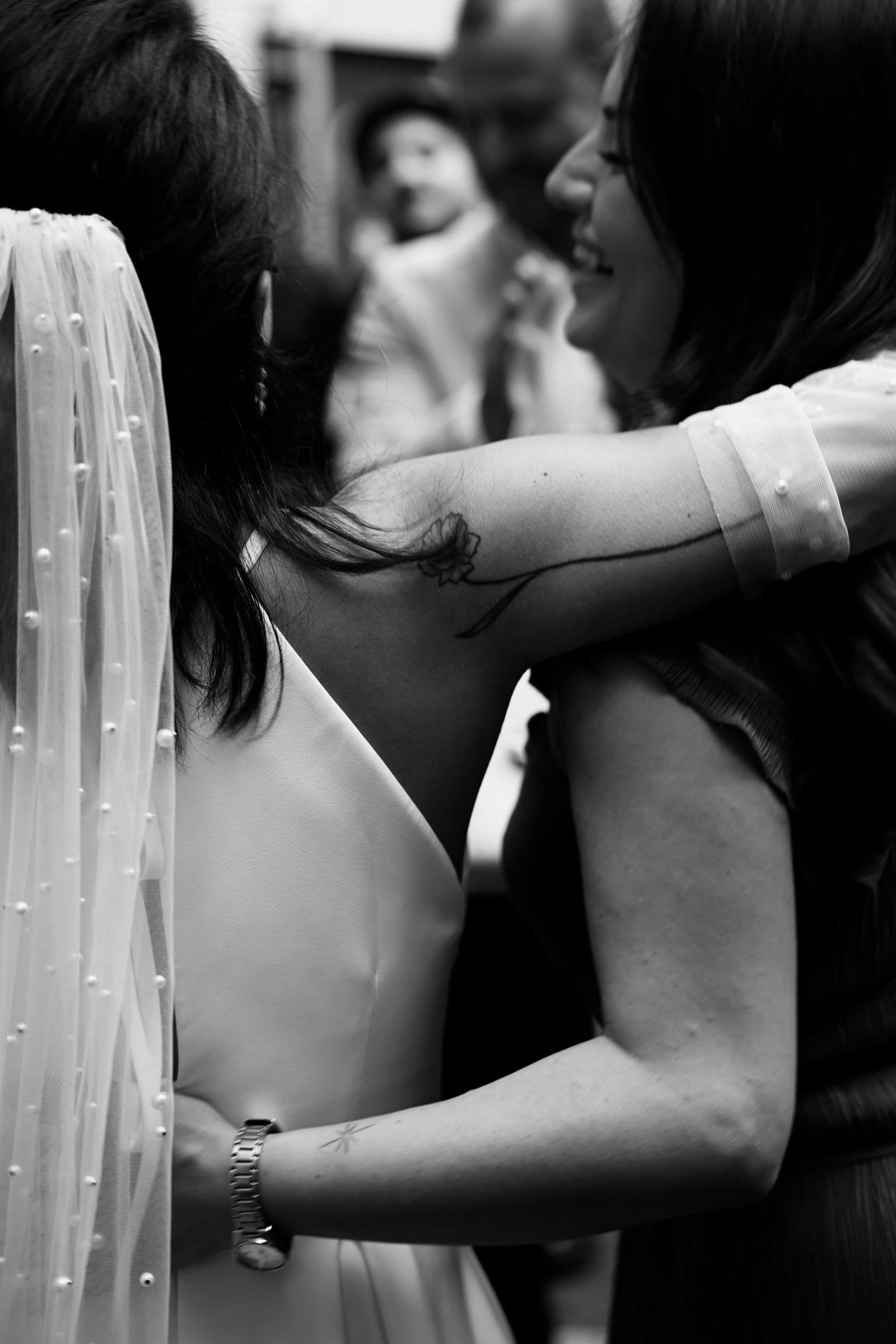 A bride embracing a guest in a candid black and white moment