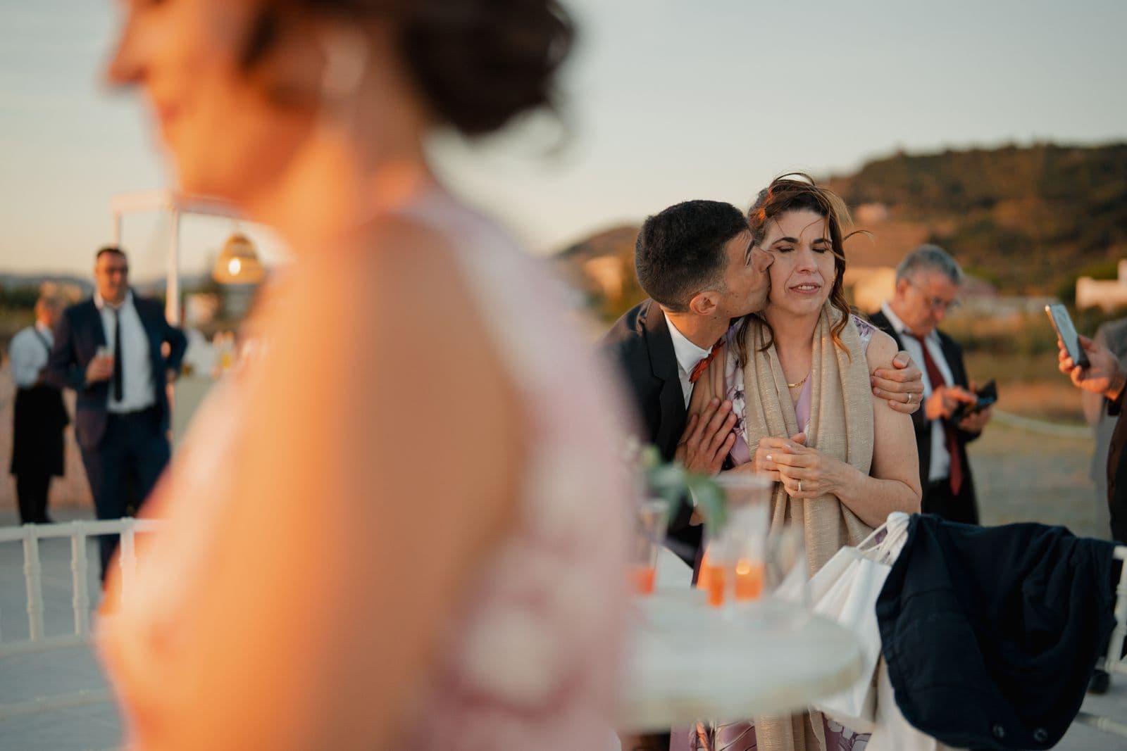 A candid emotional moment between guests at a sunset wedding reception