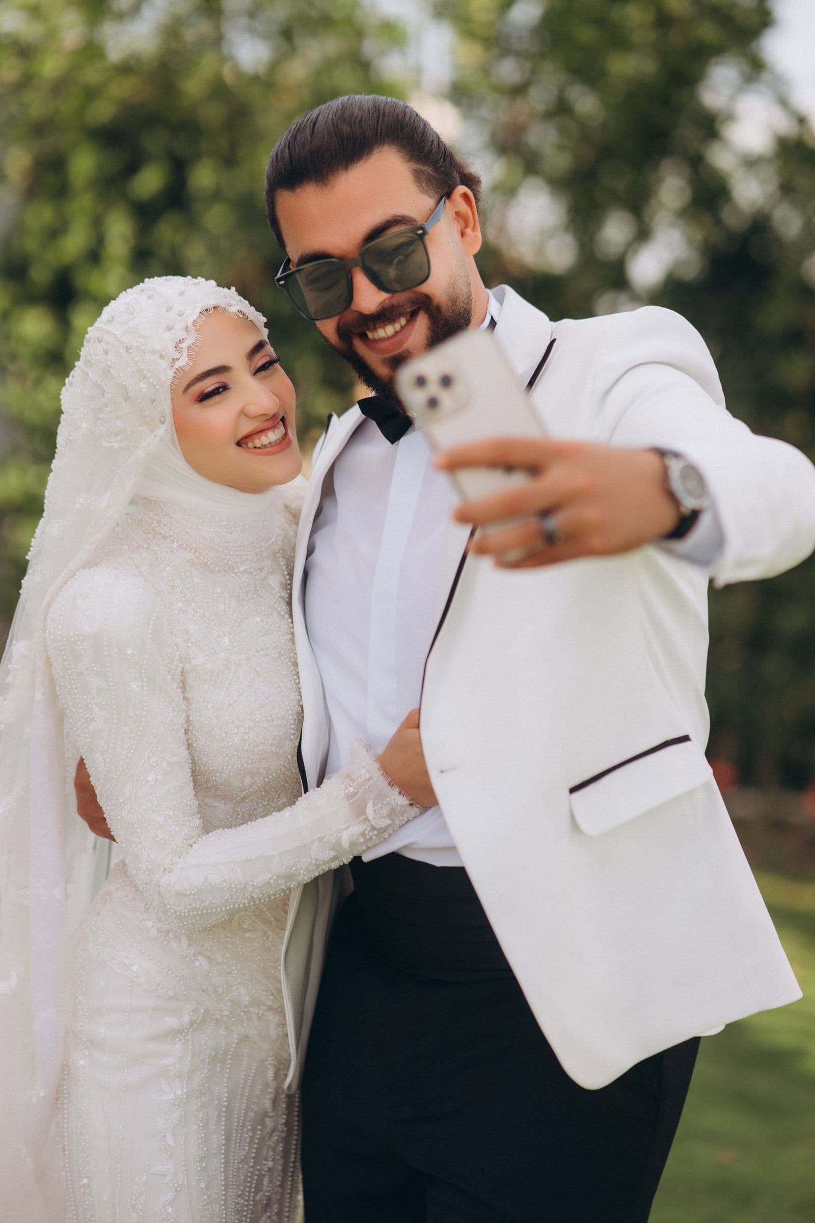 A bride and groom taking a selfie on a phone at their wedding