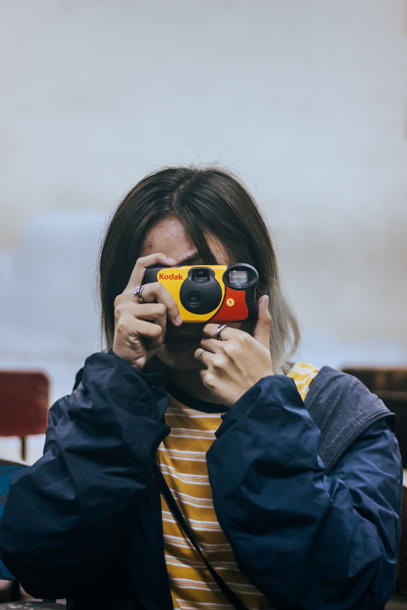 A person taking a photo with a yellow Kodak disposable camera