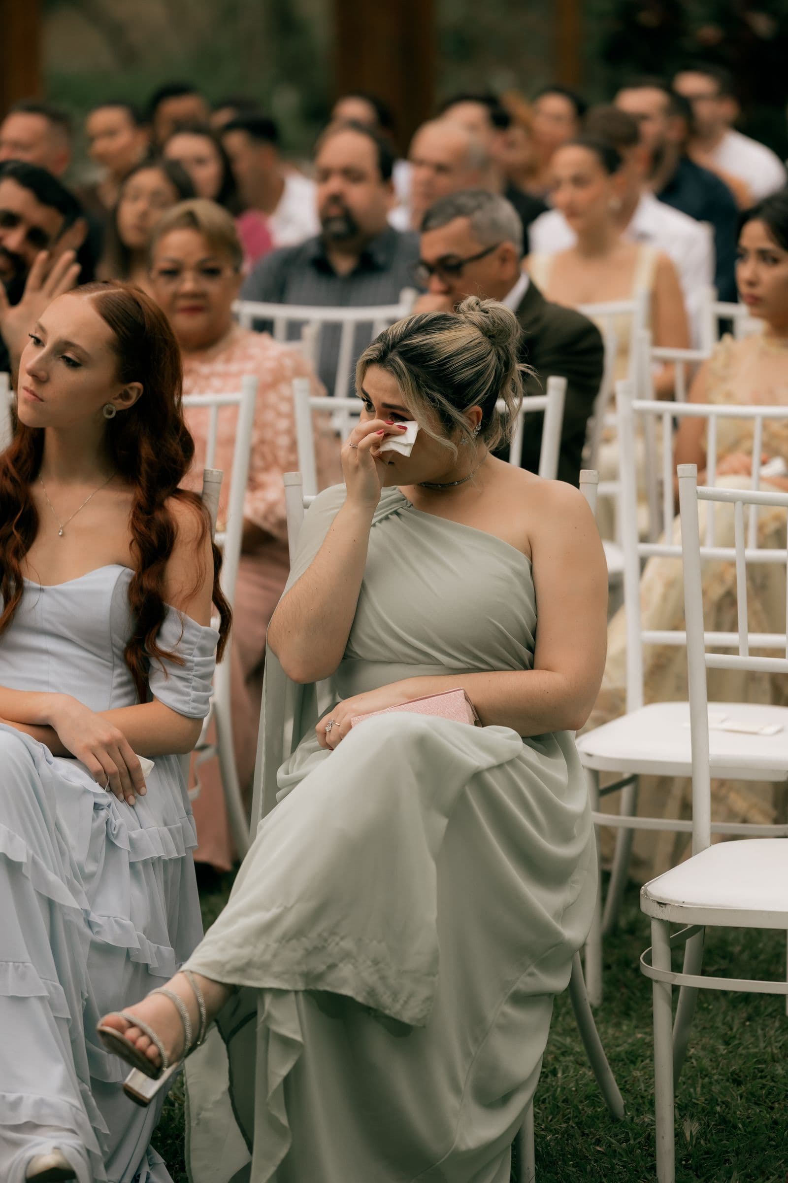 A guest wiping away tears during an emotional outdoor wedding ceremony
