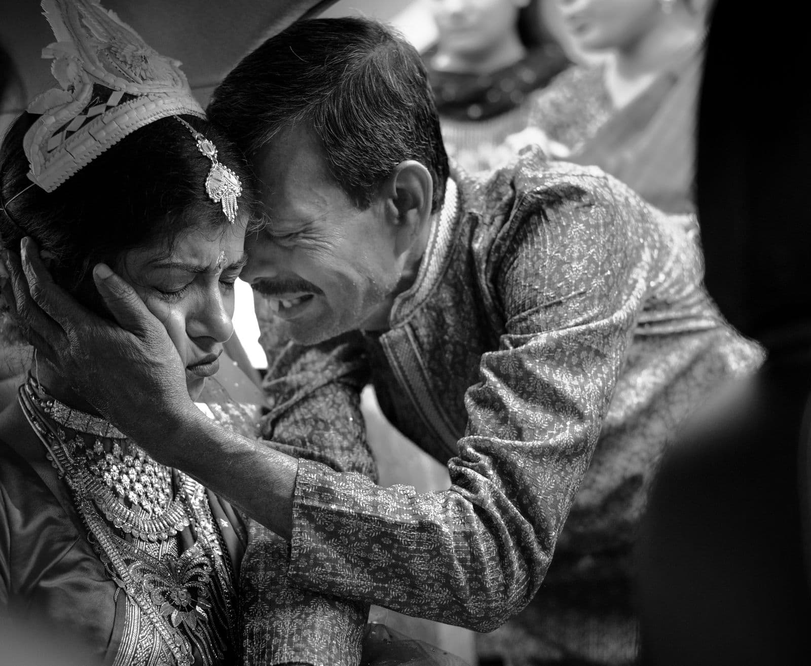 A father and bride sharing an emotional moment at a traditional wedding, in black and white