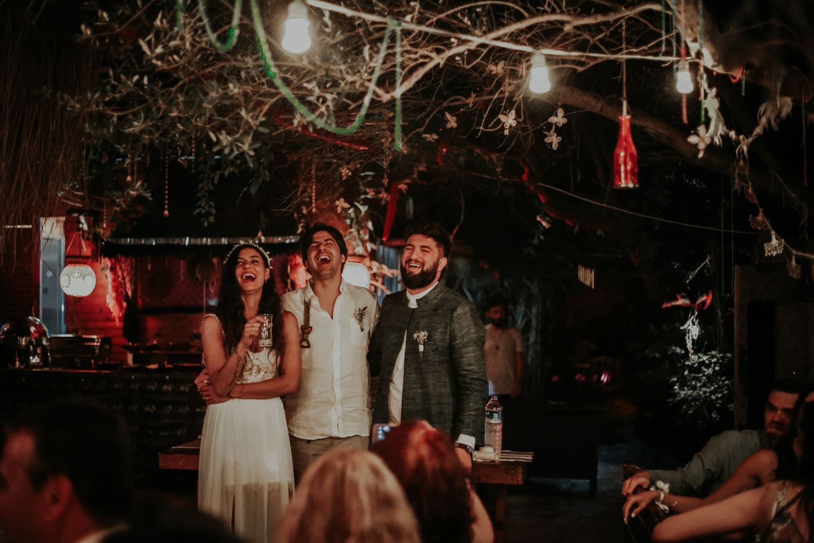 A bride and friends laughing together at an evening wedding reception