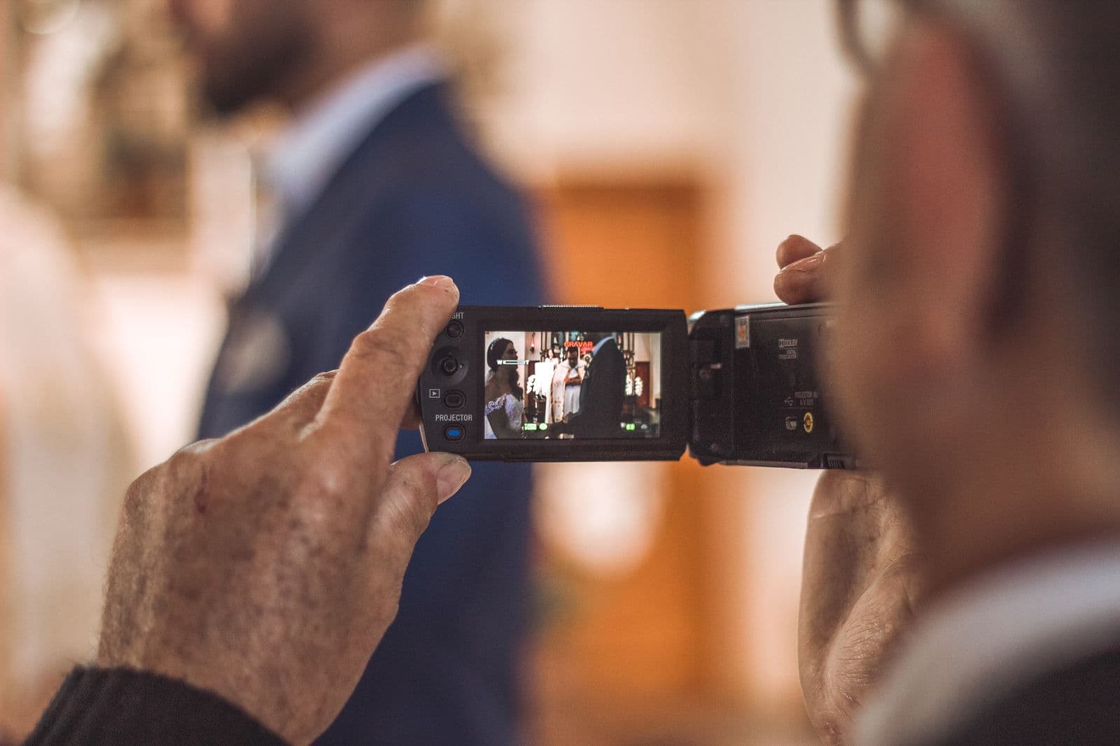 A guest filming the wedding ceremony on a handheld camcorder