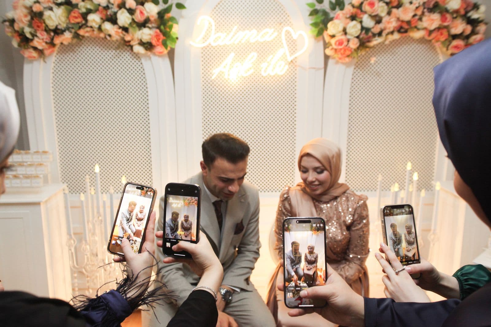 Wedding guests holding up several phones to photograph the newlywed couple
