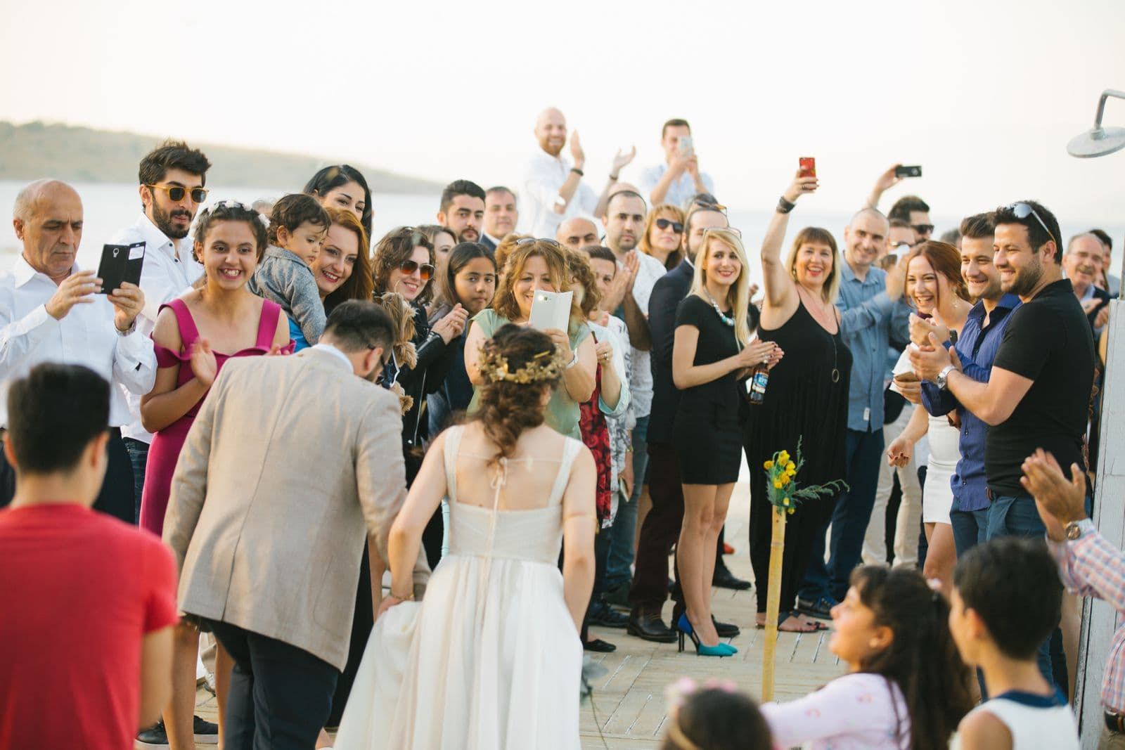 A crowd of wedding guests photographing the bride on their phones