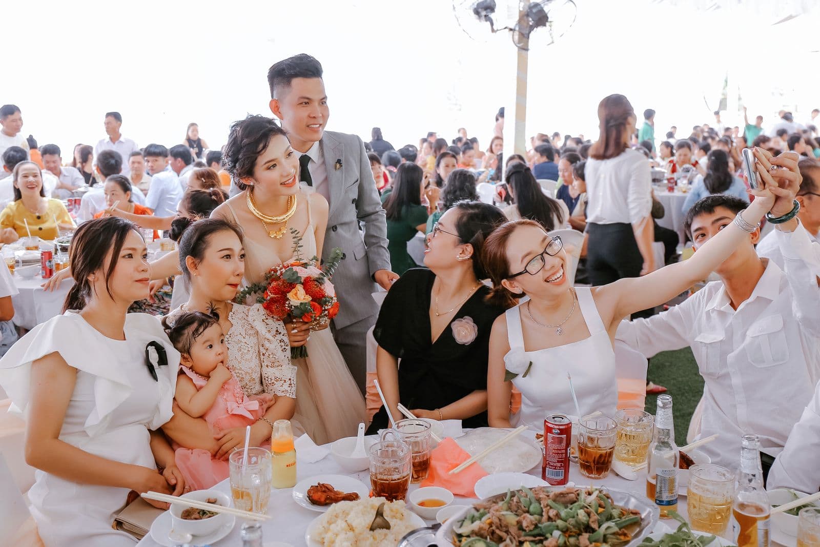 Wedding guests taking a selfie with the newlyweds on a phone during the reception meal