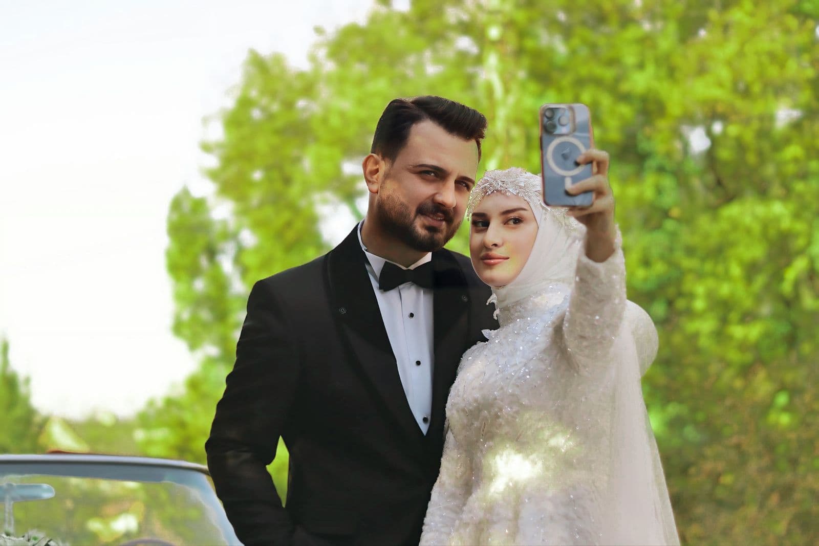 A newlywed couple taking a selfie on a phone outdoors on their wedding day