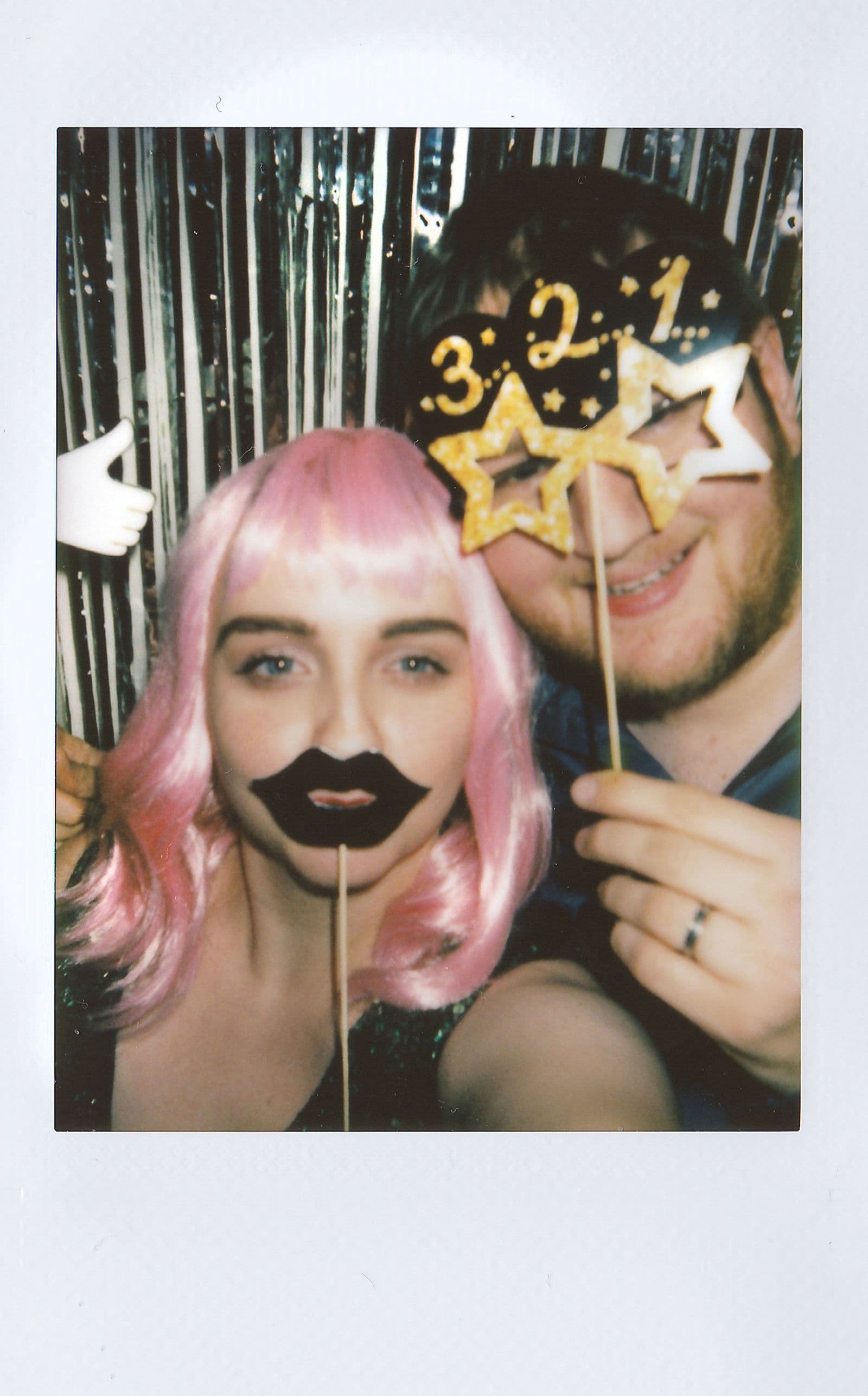 Two friends posing with novelty props at a party photo backdrop