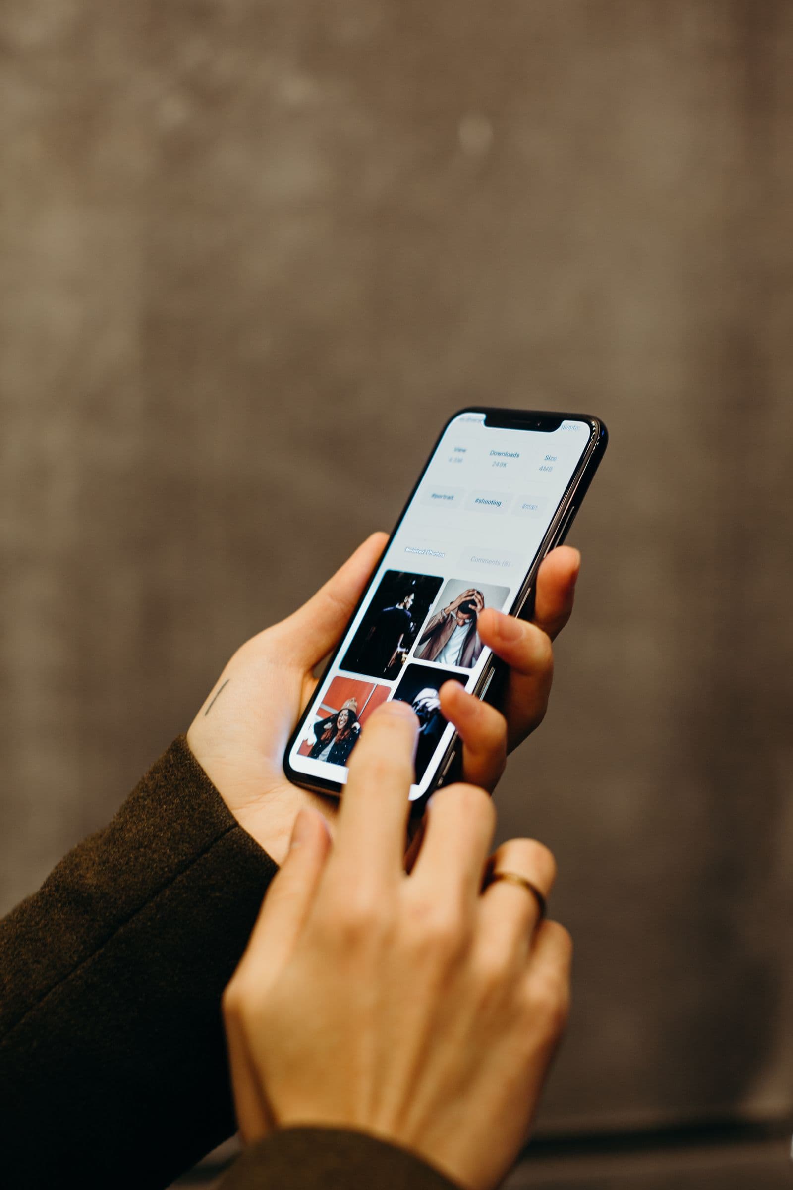 A hand holding a phone showing a photo-sharing app with a grid of images