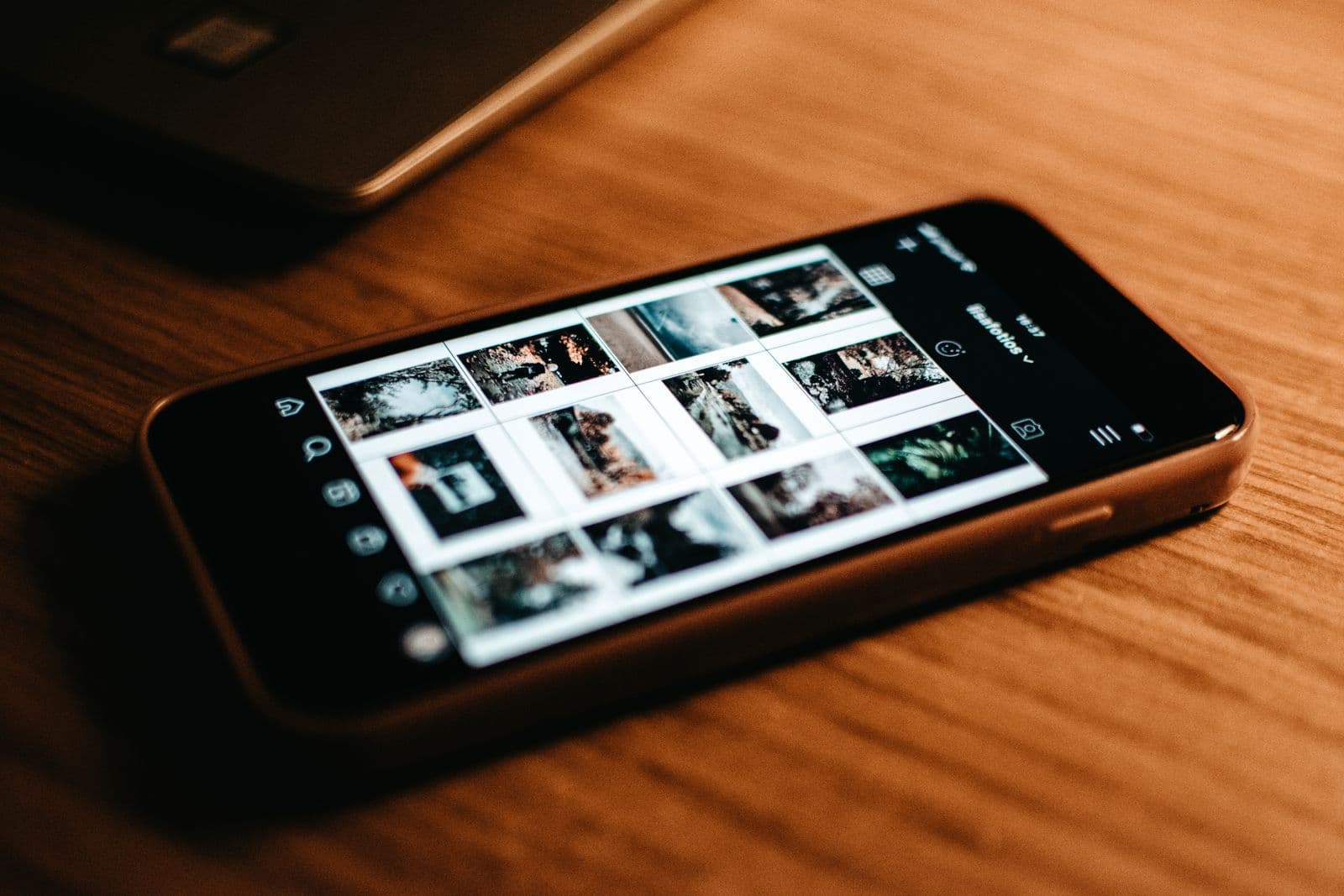 A phone on a desk showing a grid gallery of photos