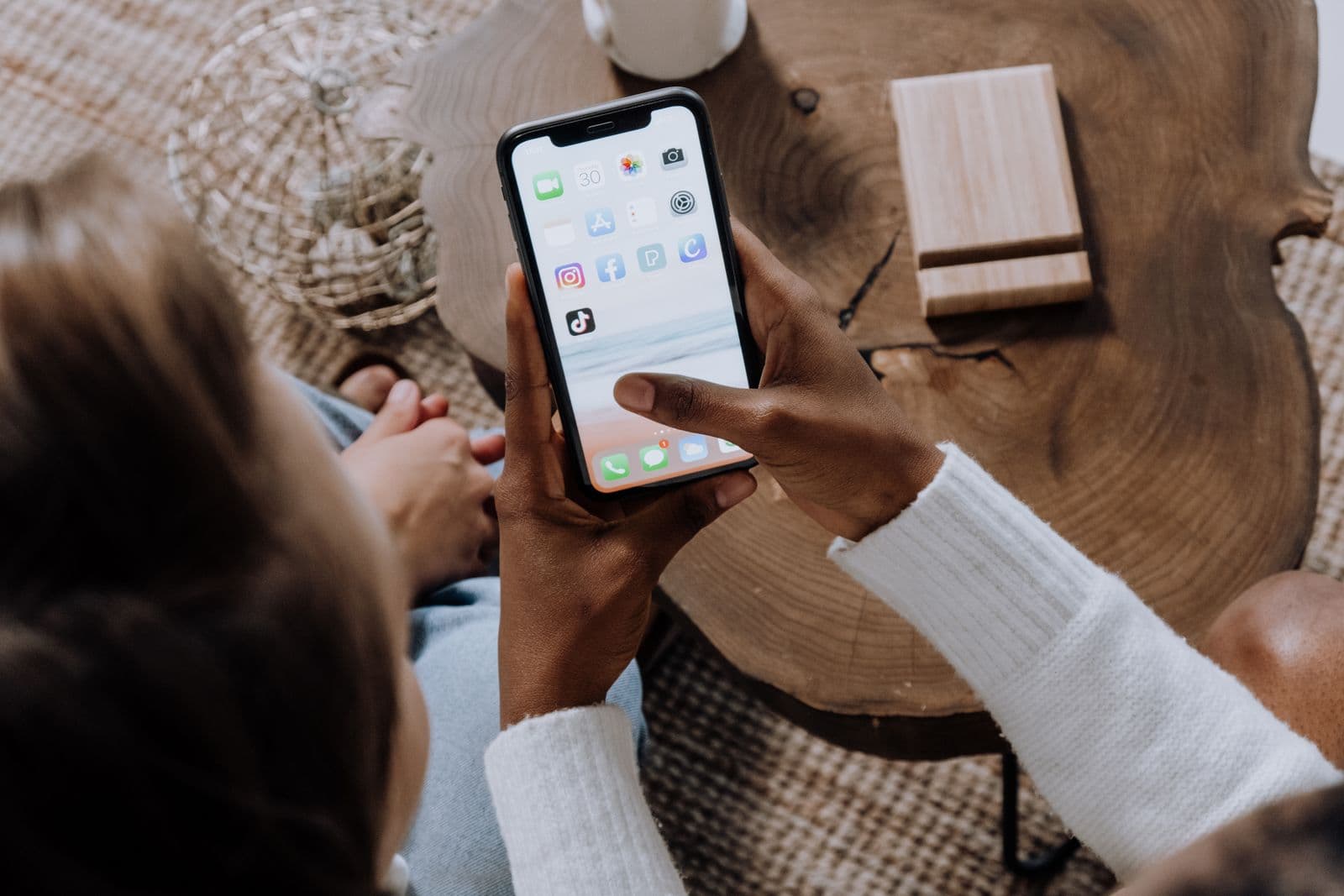 A person holding a phone showing social media apps including Instagram