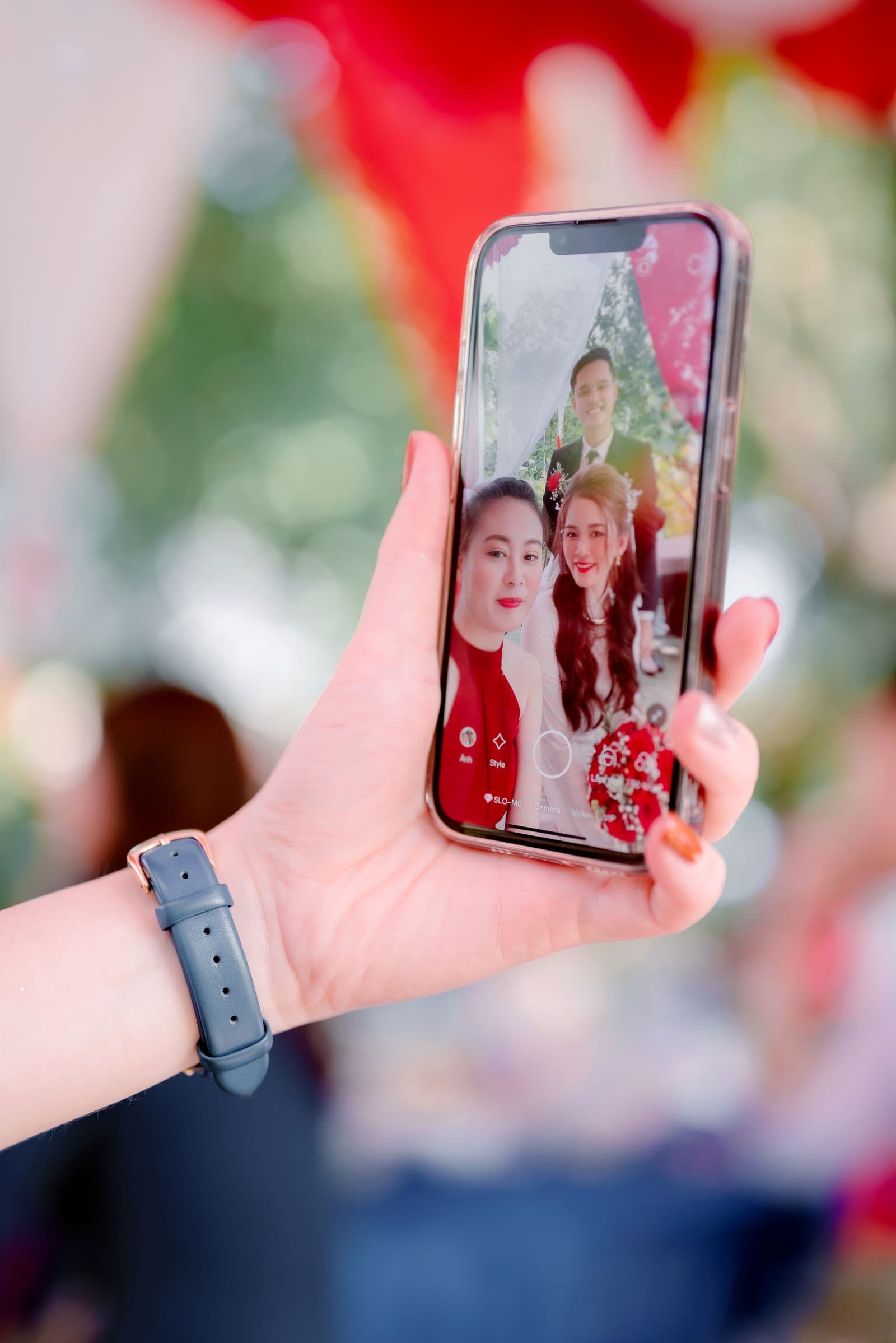 A hand holding a phone showing a wedding selfie of the couple