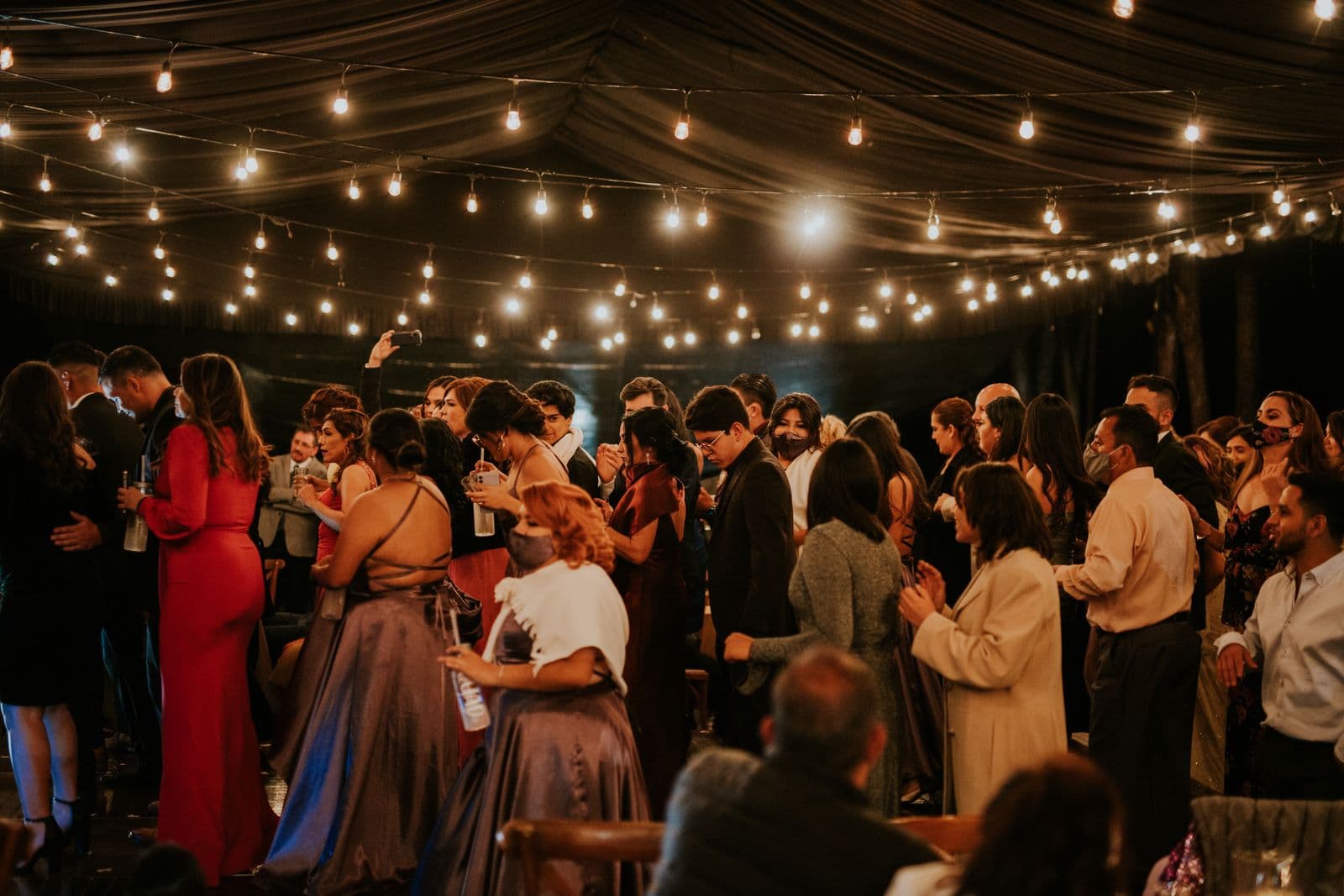 A wedding reception dance floor glowing under warm string lights as guests celebrate