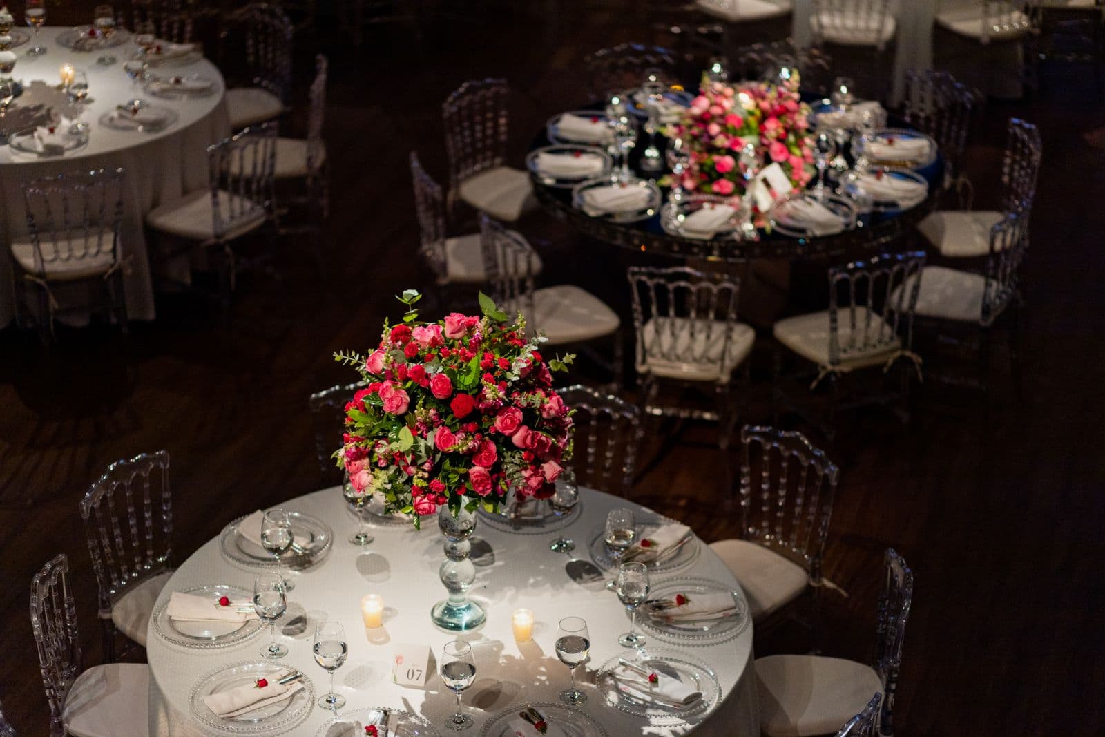 Round wedding reception tables set with floral centerpieces and table numbers, ready for photo-sharing signs