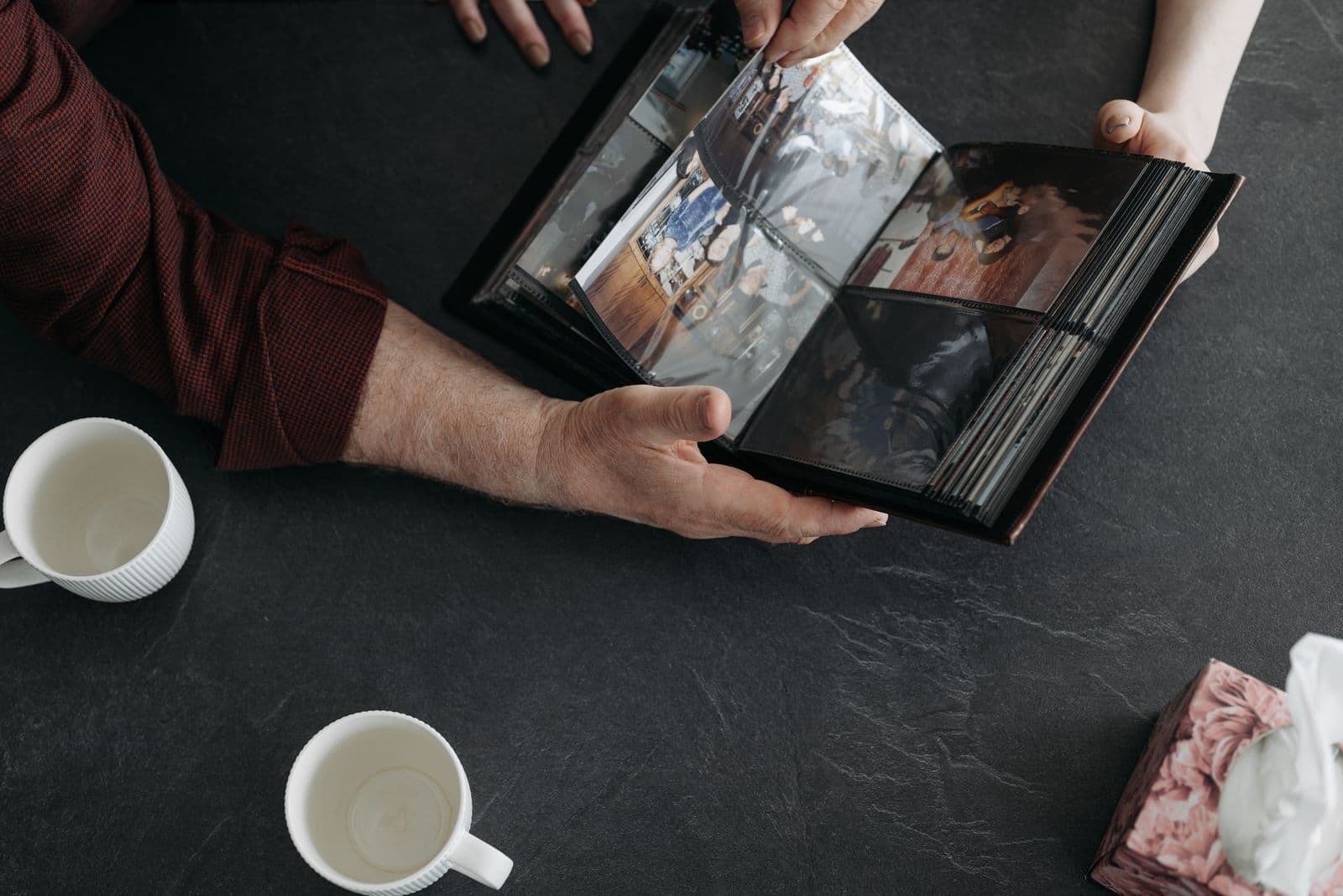 Two people looking through a wedding photo album together over coffee