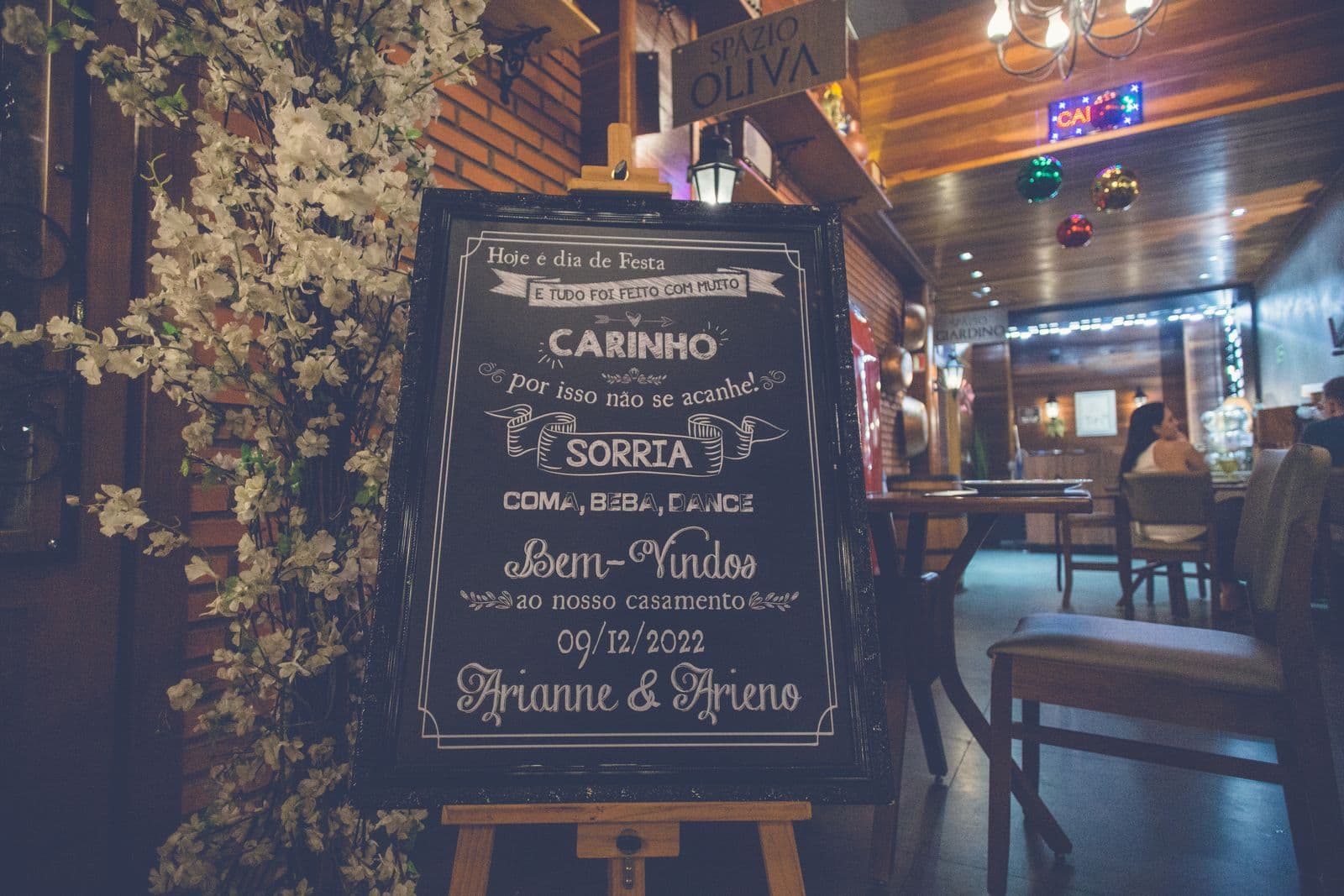 A hand-lettered chalkboard wedding welcome sign on an easel beside blossom decor