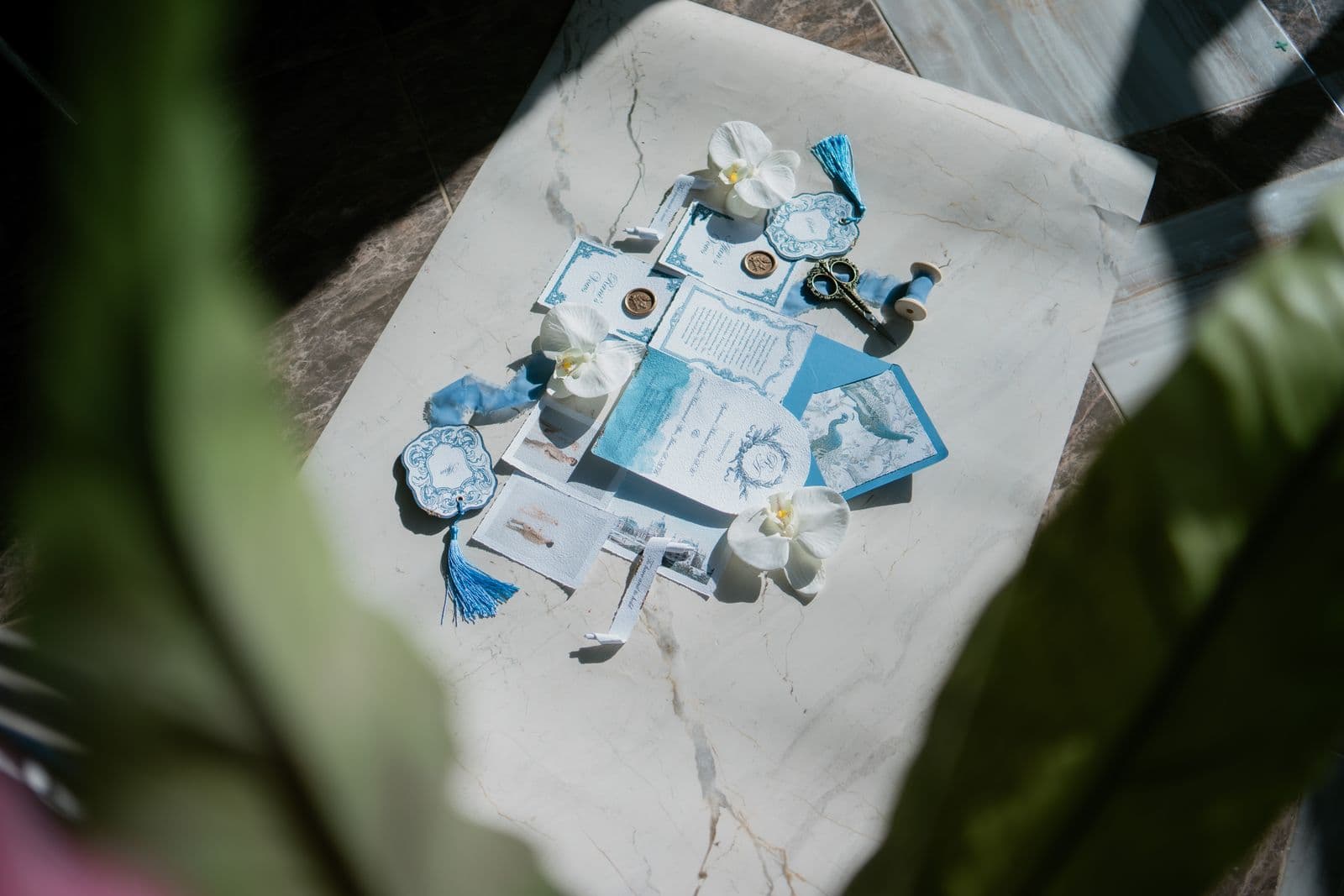 A flat lay of wedding invitations, rings, and details on a marble surface