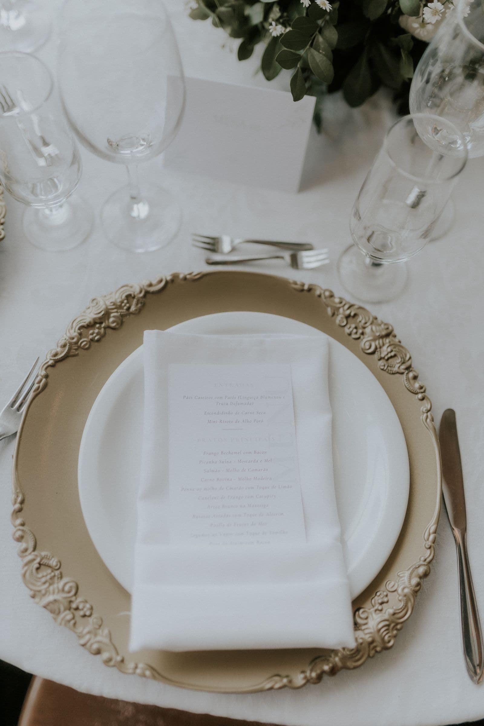 An elegant wedding place setting with a printed menu card on a gold charger plate