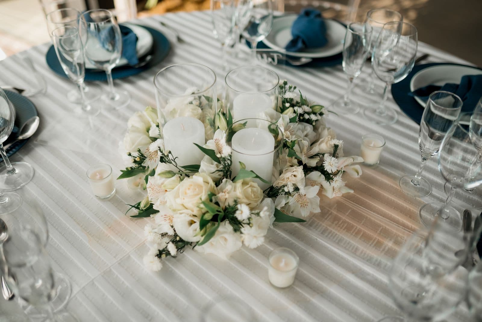 A wedding reception table set with a white floral and candle centerpiece
